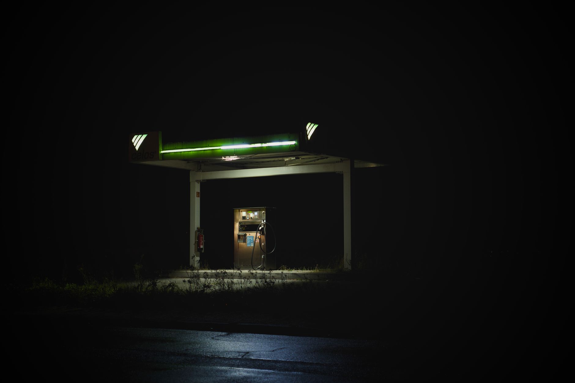 Isolated gas station glowing at night against a dark background, creating a mysterious vibe.
